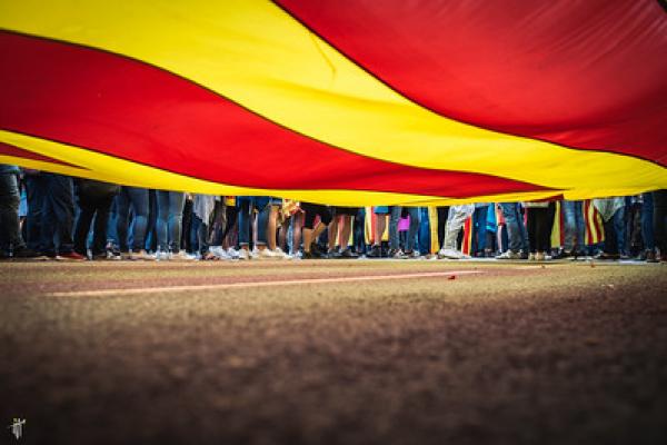 Image of people's legs and feet under red and yellow flag